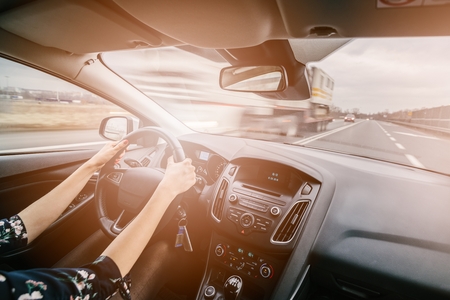 Young female driving a car. Driving a car. Sunny day. Modern car interiorの写真素材