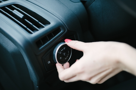 Woman turning on car headlights. Modern car interiorの写真素材