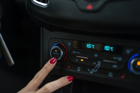 Woman turning on car air condition. Modern car interiorの写真素材