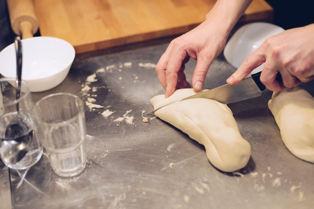 Cutting uncooked dough on pieces with knifeの写真素材