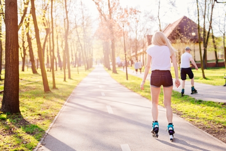 Back view on beauty young woman roller skating on the park roadの写真素材