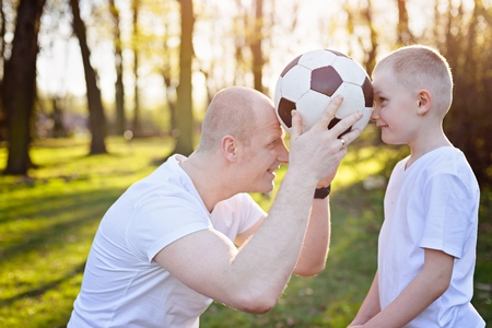 Young father and son playing with ball on green grass in park. Happy family in the parkの写真素材