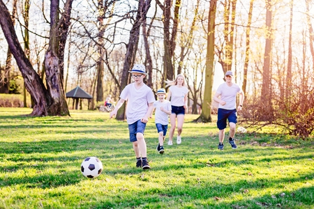 Family playing football on green grass in park. Happy family in the parkの写真素材