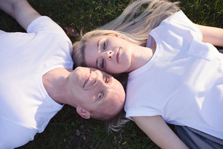 Happy romantic couple lying on grass in park. Happy family in the parkの写真素材