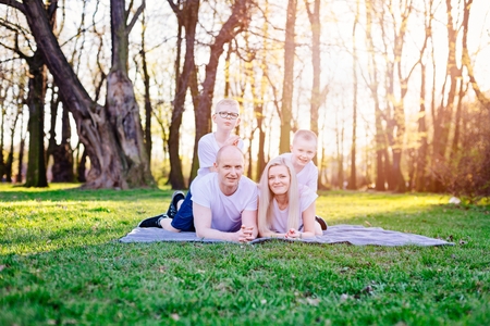 Parent and children lying on grass in park. Happy family in the parkの写真素材