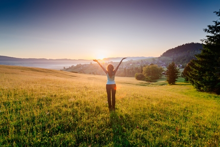Woman enjoying beautiful sunrise at mountains. Freedom and relax conceptの写真素材