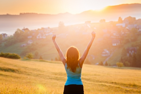 Young happy woman with raised arms in mountains. Freedom and relax conceptの写真素材