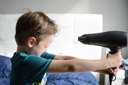 Little child boy playing with electrical hair dryerの写真素材