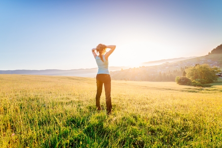 Woman at summer meadow enjoying beauty morning in mountains and celebrating new day. Female enjoying life at sunny morning.の写真素材