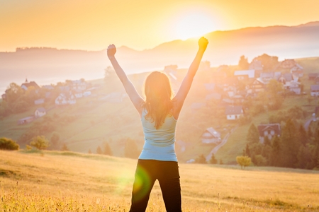 Happy young woman at mountains. Female enjoying life at sunny morning. Relaxation conceptの写真素材