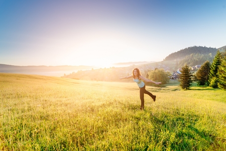 Woman at summer meadow enjoying beauty morning in mountains and celebrating new day. Female enjoying life at sunny morning.の写真素材