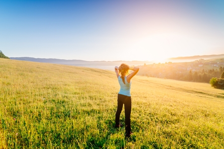 Woman at summer meadow enjoying beauty morning in mountains and celebrating new day. Female enjoying life at sunny morning.の写真素材