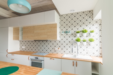 Modern white kitchen cabinets with Induction hob. Open bright kitchen with white furniture. Island kitchen. Turquoise lamps and curtains. Modern, bright attic apartment.の写真素材