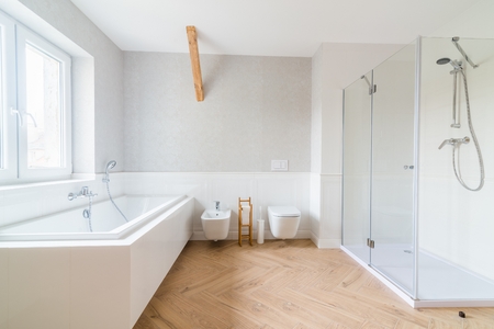 Bathtub and glass shower cabin in loft bathroom. Modern, bright attic apartment.の写真素材