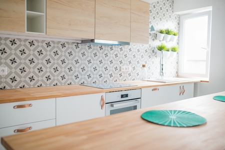 Modern white kitchen cabinets with Induction hob. Open bright kitchen with white furniture. Island kitchen. Turquoise lamps and curtains. Modern, bright attic apartment.の写真素材