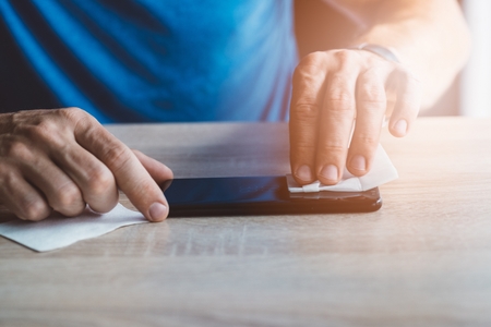 Man cleaning smartphone screen with cloth before applying protective cover foil