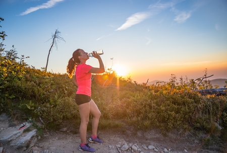 Woman drinking water from water bottle. Woman trail runner. Szczyrk, Beskidy Mountains, Polandの写真素材