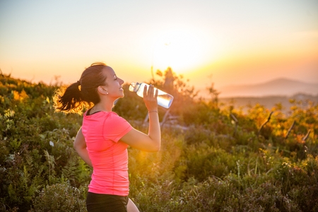 Thirsty woman trail runner drinking water from water bottle. Szczyrk, Beskidy Mountains, Polandの写真素材