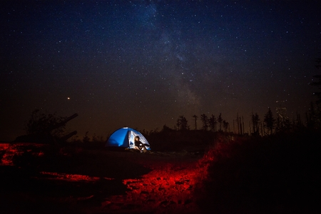 Young woman pouring coffee from thermos in night camp on mountain trail. Szczyrk, Beskidy Mountains, Polandの写真素材