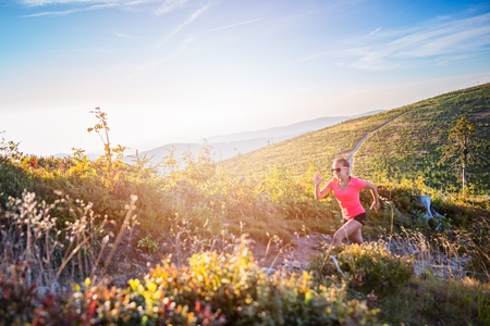 Young beautiful woman running in mountains. Woman trail runnerの写真素材