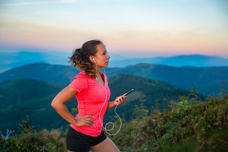 Young woman listening to the music during trail running in mountains. Szczyrk, Beskidy Mountains, Silesian Beskid, Polandの写真素材