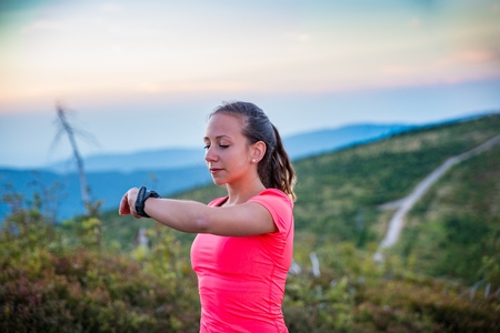 Woman checking time on her sport watch during trail running in mountains. Szczyrk, Beskidy Mountains, Silesian Beskid, Polandの写真素材