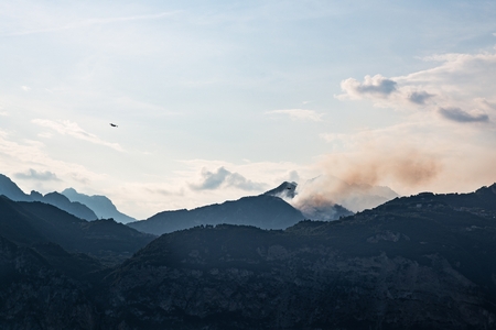 Burning forest in Italian mountains in Brescia province. Forest fire and firefighter planes.の写真素材