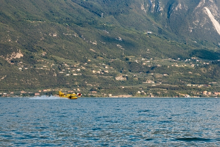 Firefighter plane taking water from Garda lake during forest fire in Italyの写真素材