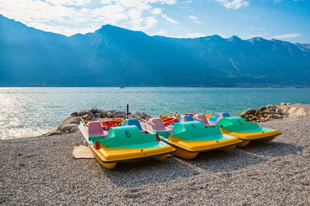 Pedal boat on the beach over Lake Garda in Limone sul Garda, Lombardy, Italyの写真素材