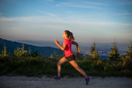 Young woman cross running in the mountains. Female trail runnerの写真素材