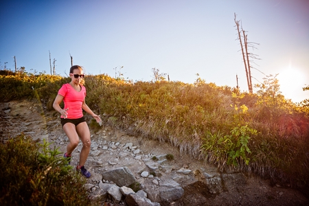 Girl trail running. Young woman cross running in the mountains.の写真素材