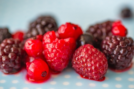 Melting fruits on the plate. Melting frozen raspberry and blackberryの写真素材