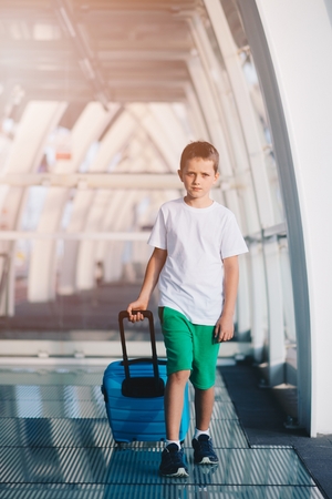 Alone ten years old child with blue baggage on airport or train station.の写真素材
