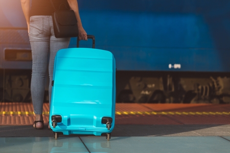 Woman with blue baggage waiting for train on train station platformの写真素材