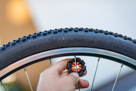 Service technician centering bike wheel with dedicated spoke wrench. Bike serviceの写真素材
