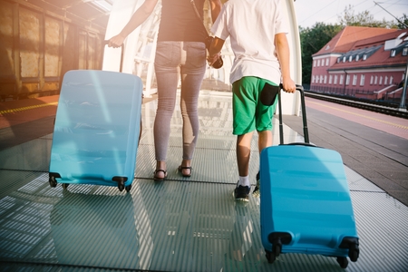 Mother and son with blue baggage suitcase walking on train station platform and waiting for trainの写真素材