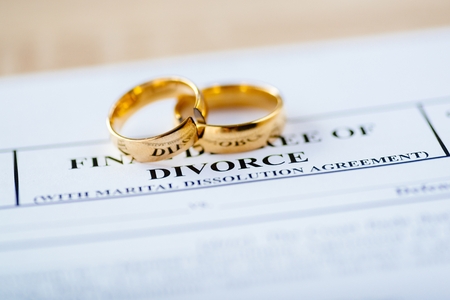 Two broken golden wedding rings divorce decree document. Divorce and separation conceptの写真素材