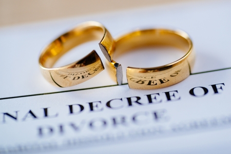 Two broken golden wedding rings divorce decree document. Divorce and separation conceptの写真素材