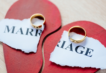 Divorce and separation concept. Two broken golden wedding rings on broken red heart.の写真素材