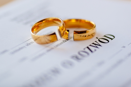 Divorce decree in Polish language and two broken wedding rings. Divorce and separation conceptの写真素材
