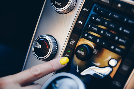 Woman turning on air conditioner on car automatic air conditioner panelの写真素材