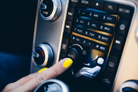 Woman turning on auto mode on car automatic air conditioner panelの写真素材