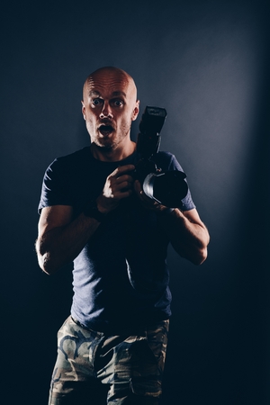 Shocked male photographer portrait in studio. Photographer with dslr cameraの写真素材
