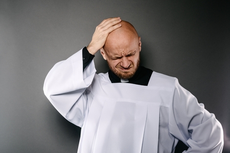 Confused catholic priest in white surplice and black shirt with cleric collarの写真素材