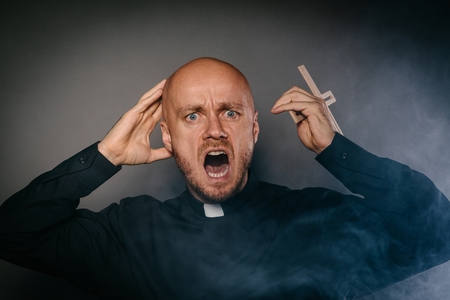 Scared frightened catholic priest in black shirt and white collarの写真素材