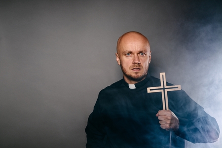 Scared frightened exorcist catholic priest in black shirt and white collarの写真素材