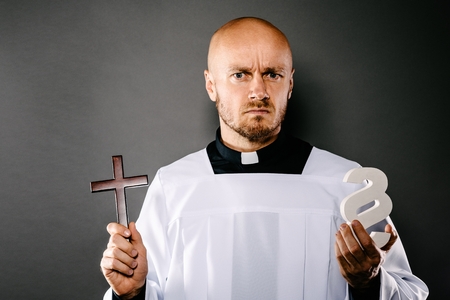 Catholic priest in white surplice holding crucifix and paraphaph. Symbols of law and religion. Church harassment and crime conceptの写真素材