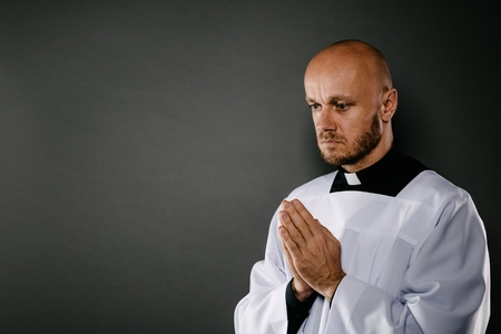 Catholic priest in white surplice meditates and praysの写真素材