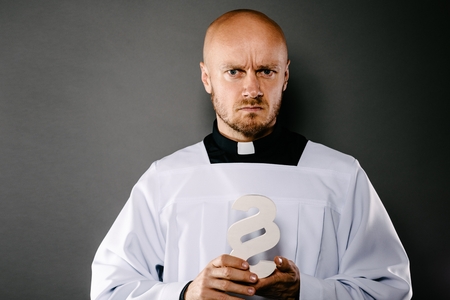 Catholic priest in white surplice holding paraphaph. Symbols of law and religion. Church harassment and crime conceptの写真素材