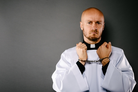 Handcuffed Catholic priest. Church harassment and crime conceptの写真素材